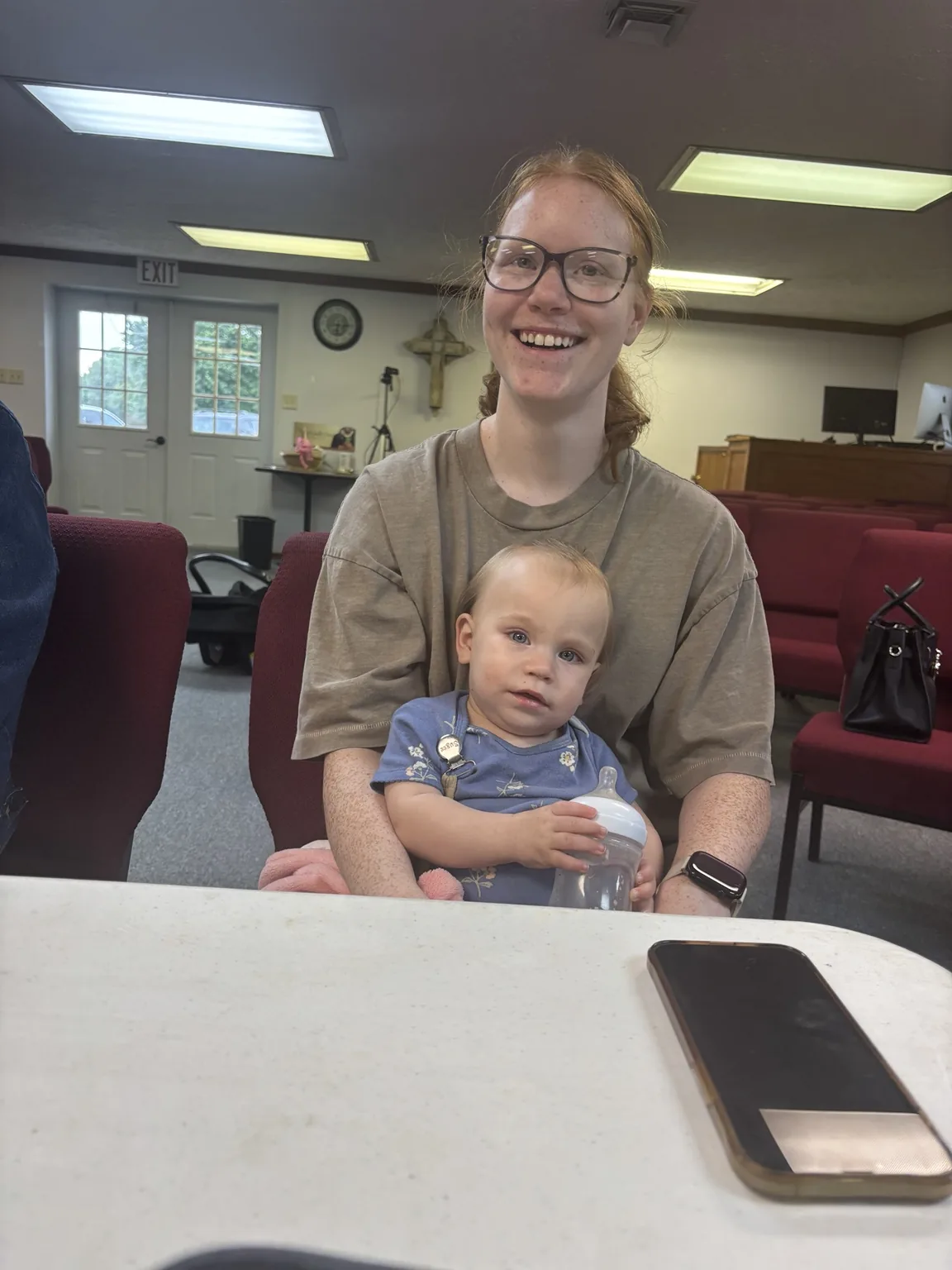 A smiling mother holding a young child inside the church